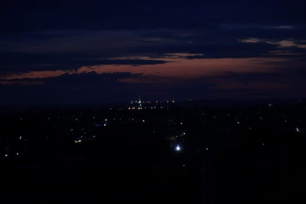 A city at night with a dark sky

Description automatically generated