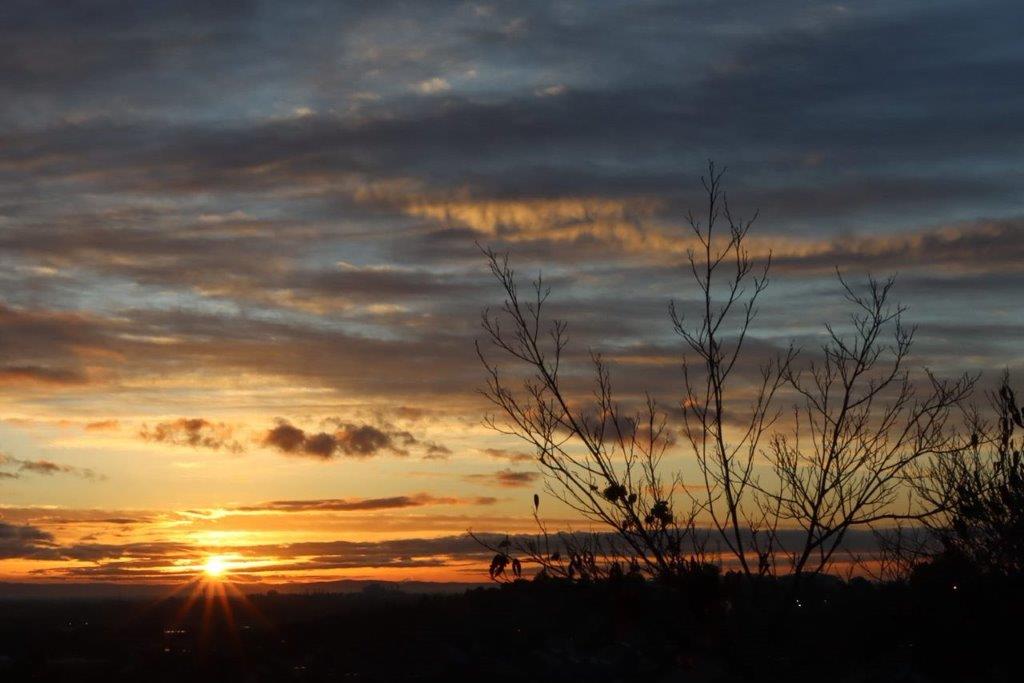 A sunset with clouds and trees

Description automatically generated