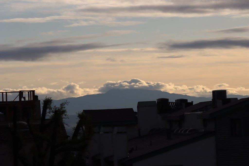 A silhouette of a building with a mountain in the background

Description automatically generated