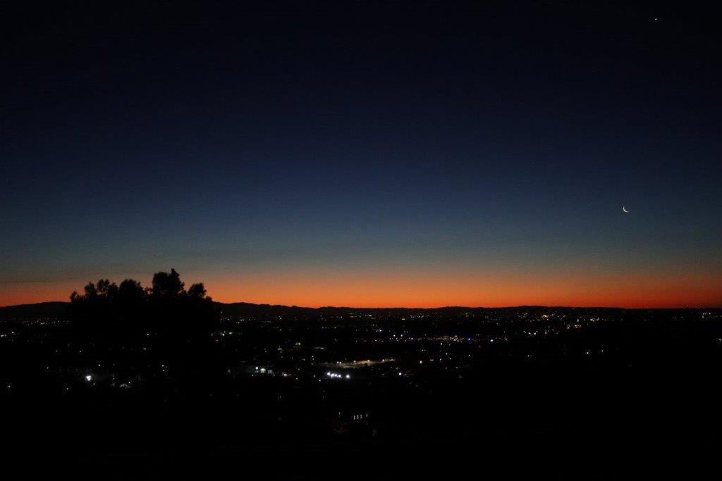 A city at night with a bright orange sky

Description automatically generated