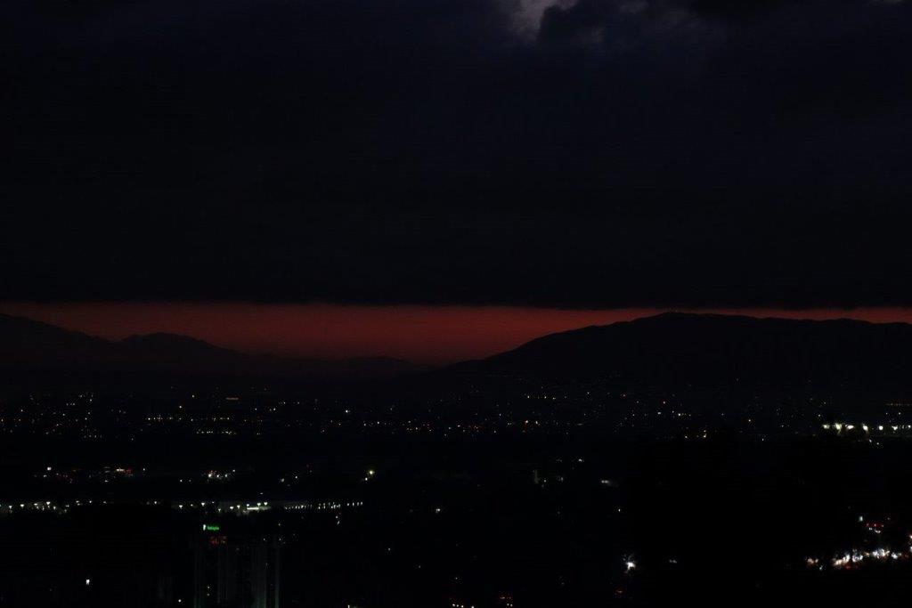 A city at night with a red sky

Description automatically generated