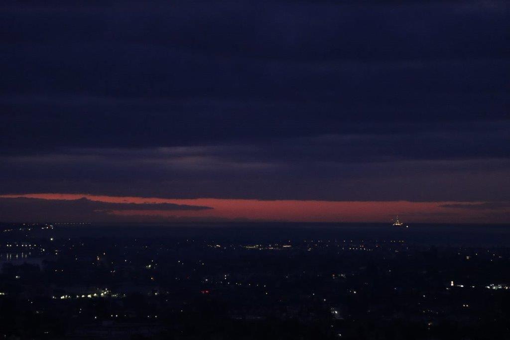 A city at night with a pink sunset

Description automatically generated