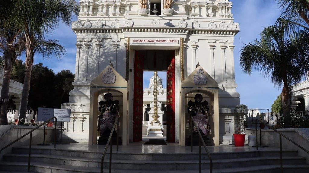 A white building with a statue in the front

Description automatically generated