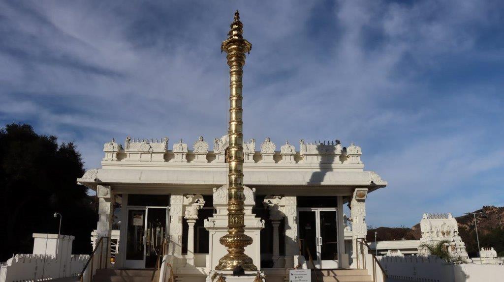 A tall gold pole in front of a building

Description automatically generated