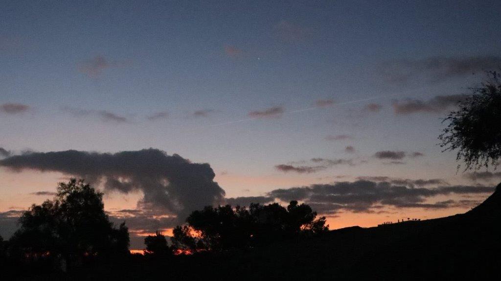 A sunset with clouds and trees

Description automatically generated
