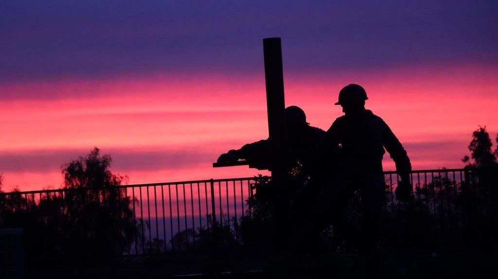 A silhouette of a couple of men working at sunset

Description automatically generated