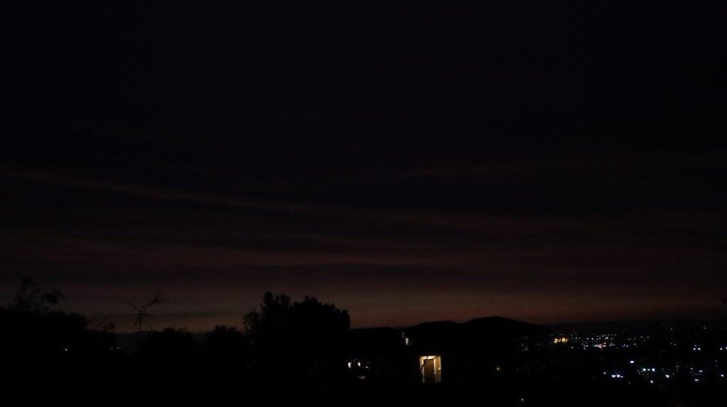 A dark sky with a few trees and a building

Description automatically generated