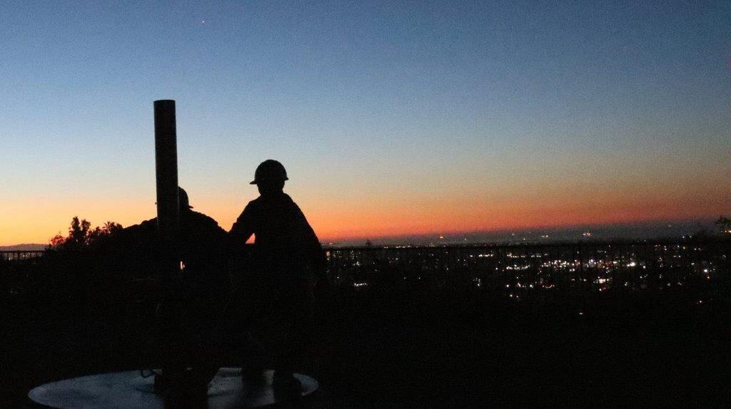Silhouette of people standing next to a pole

Description automatically generated