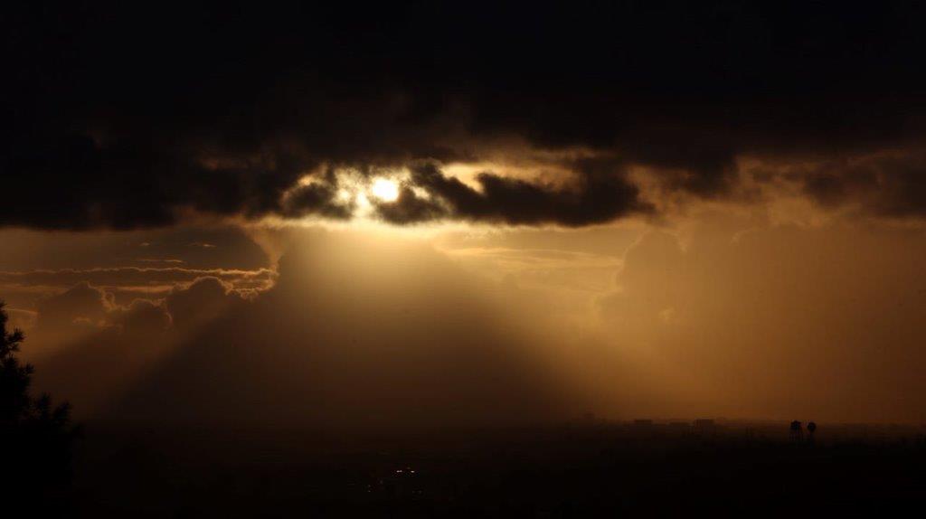 Sun shining through clouds at night

Description automatically generated