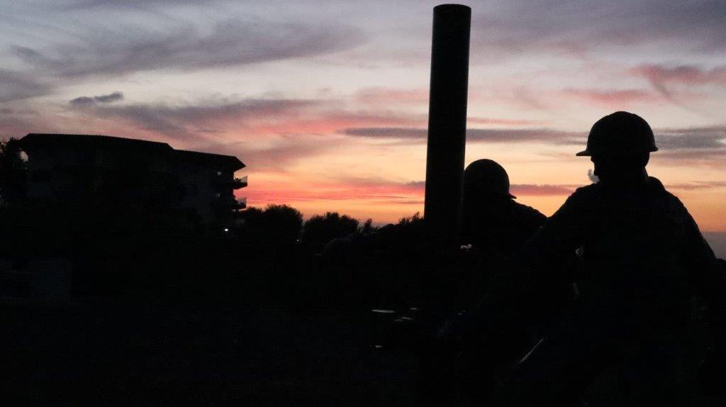 Silhouette of people standing next to a pole

Description automatically generated