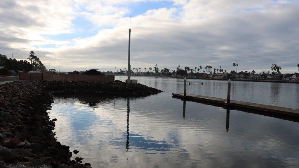 A body of water with a dock and a building in the background

Description automatically generated