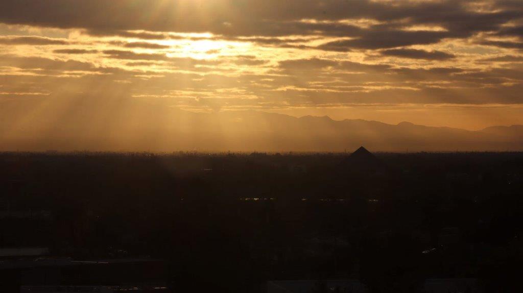 Sun shining through clouds over a city

Description automatically generated