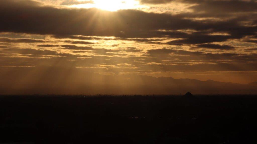 Sun shining through clouds over a city

Description automatically generated