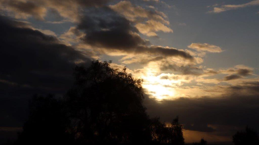 A sun setting behind clouds

Description automatically generated