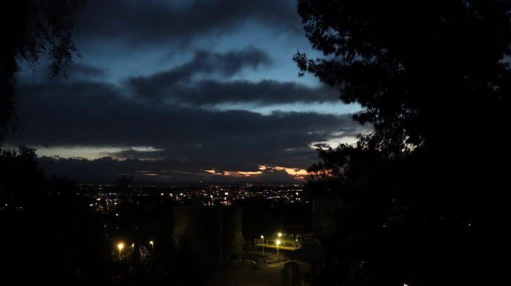 A city at night with trees and clouds

Description automatically generated