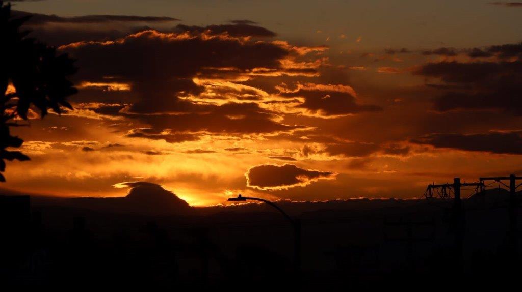 A sunset with clouds and a mountain

Description automatically generated