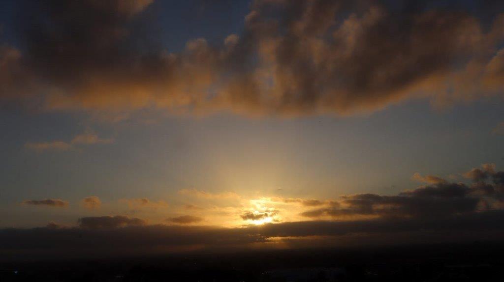 A sun setting behind clouds

Description automatically generated