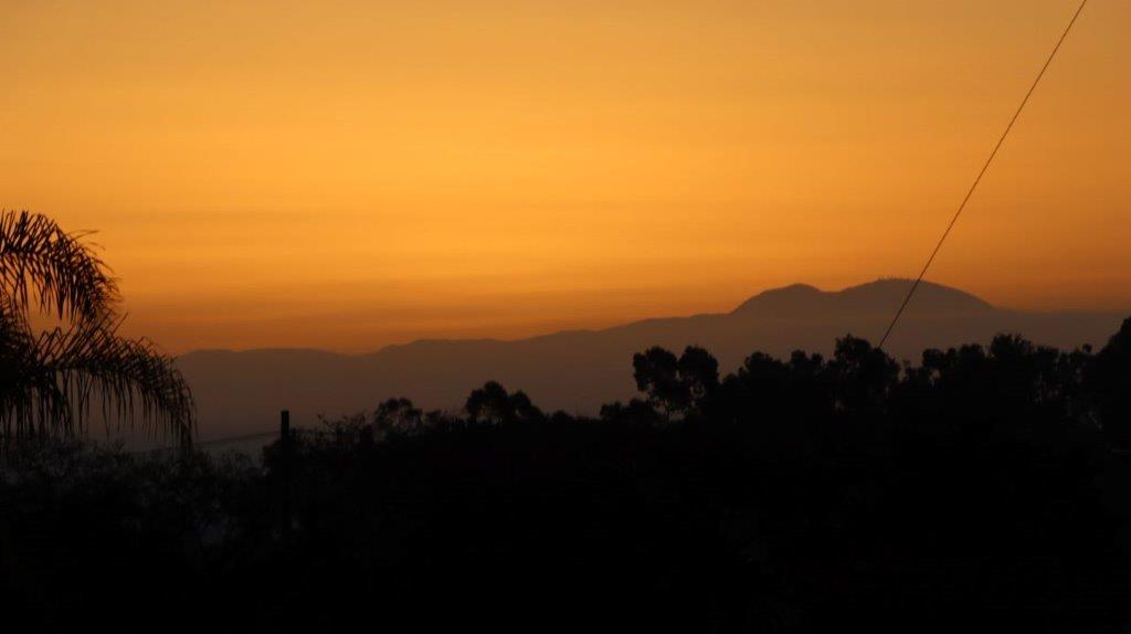 A silhouette of trees and mountains during sunset

Description automatically generated