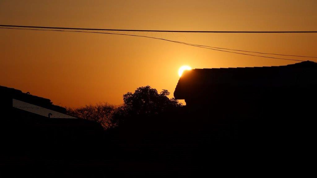 A sunset over a house

Description automatically generated