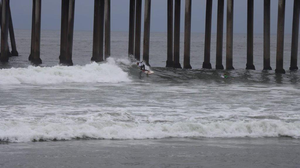 A surfer under a pier

Description automatically generated