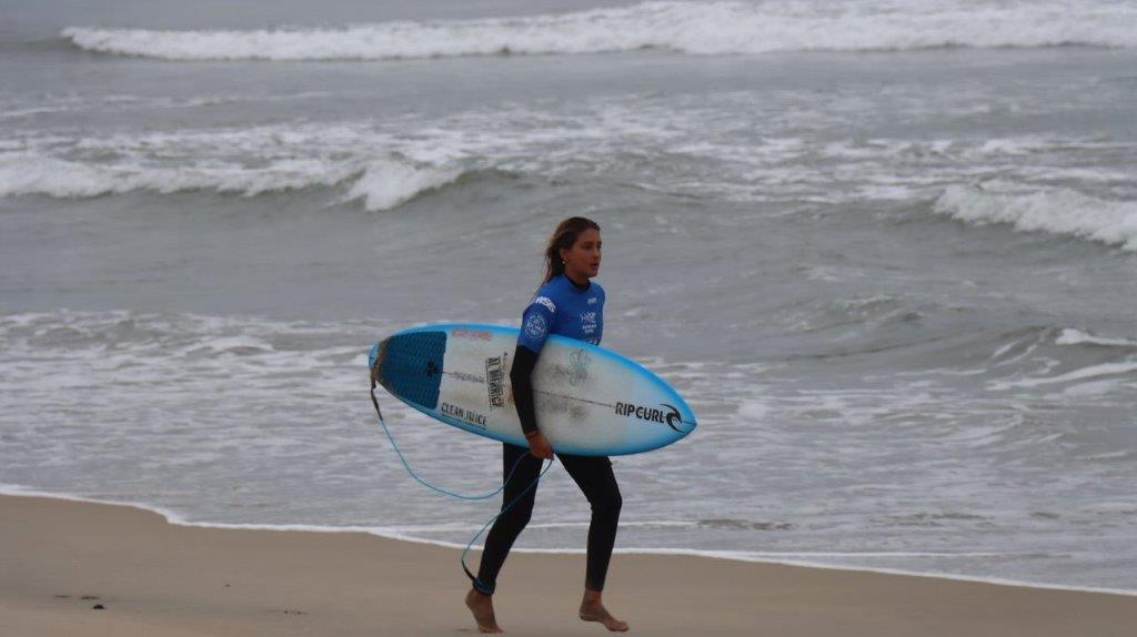 A person carrying a surfboard on a beach

Description automatically generated