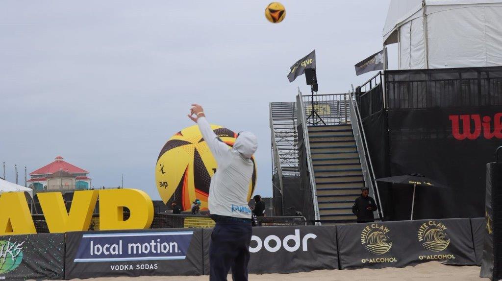 A person in a white hat reaching for a ball

Description automatically generated