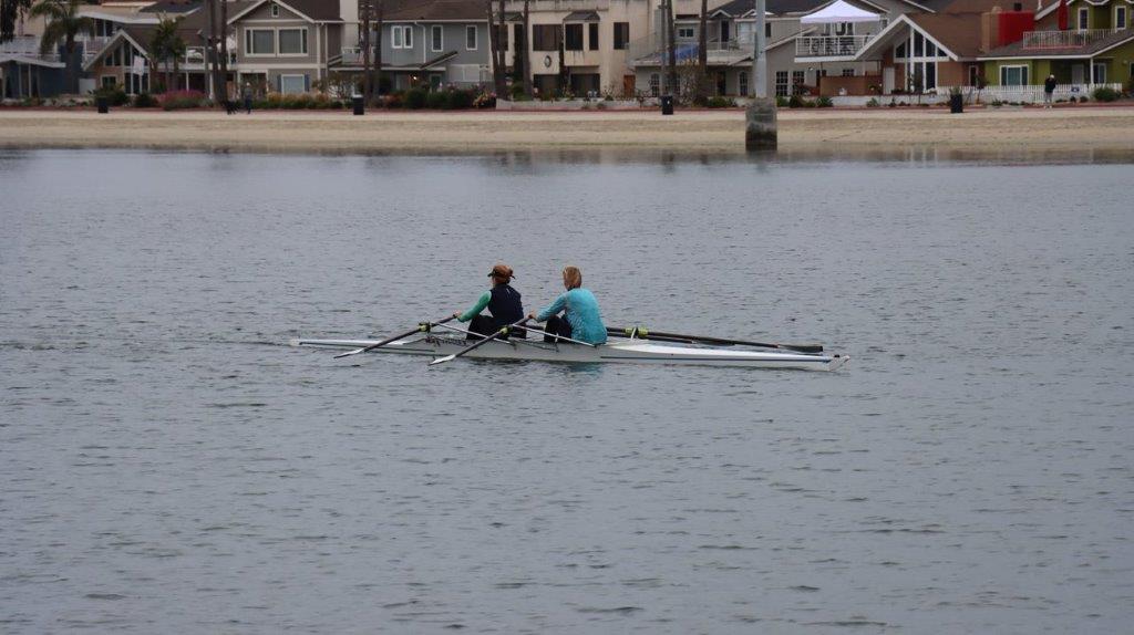 A couple of people rowing on a river

Description automatically generated