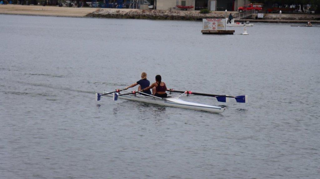 A couple of people rowing a boat

Description automatically generated